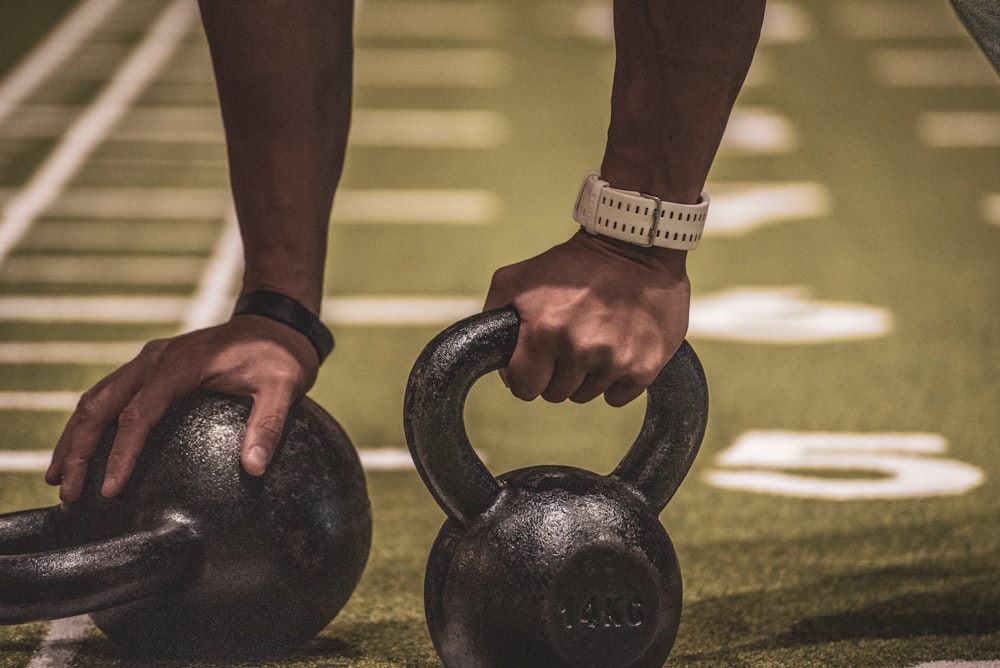 person holding black kettle bell