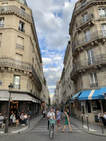 A bustling European city street lined with colorful cafes and historic buildings under a bright blue sky.