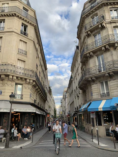A bustling European city street lined with colorful cafes and historic buildings under a bright blue sky.
