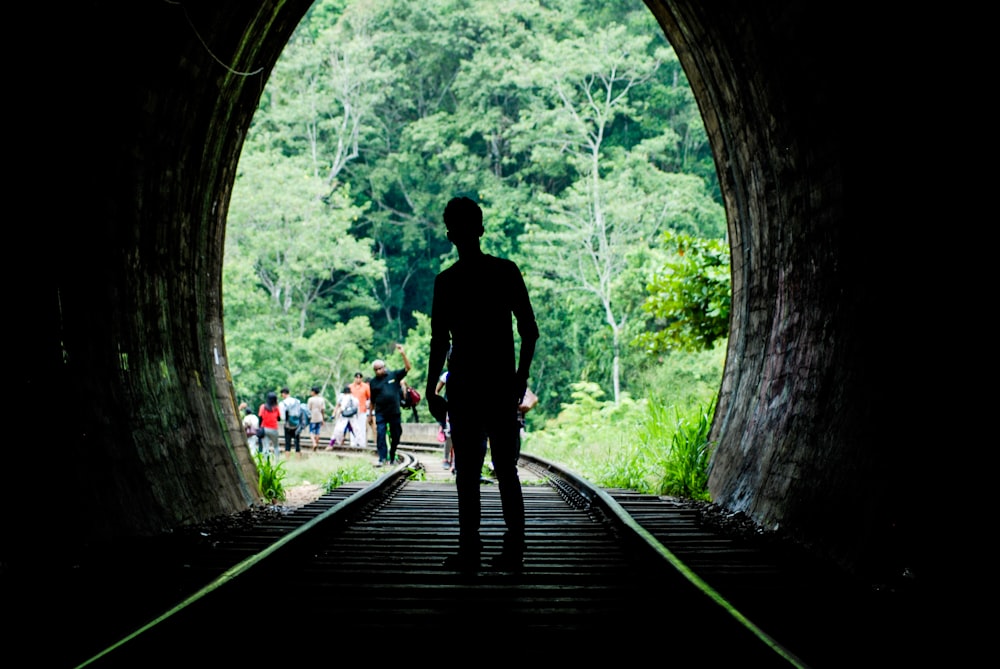 man in black jacket walking on wooden bridge