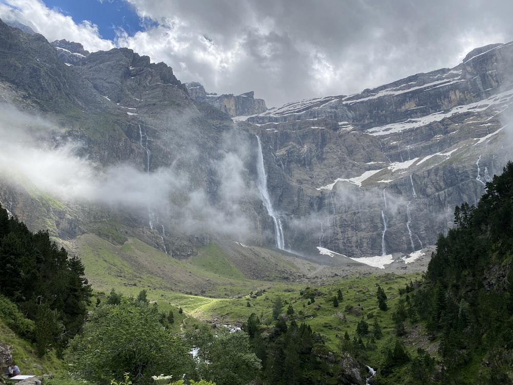 green trees near mountain under white clouds during daytime