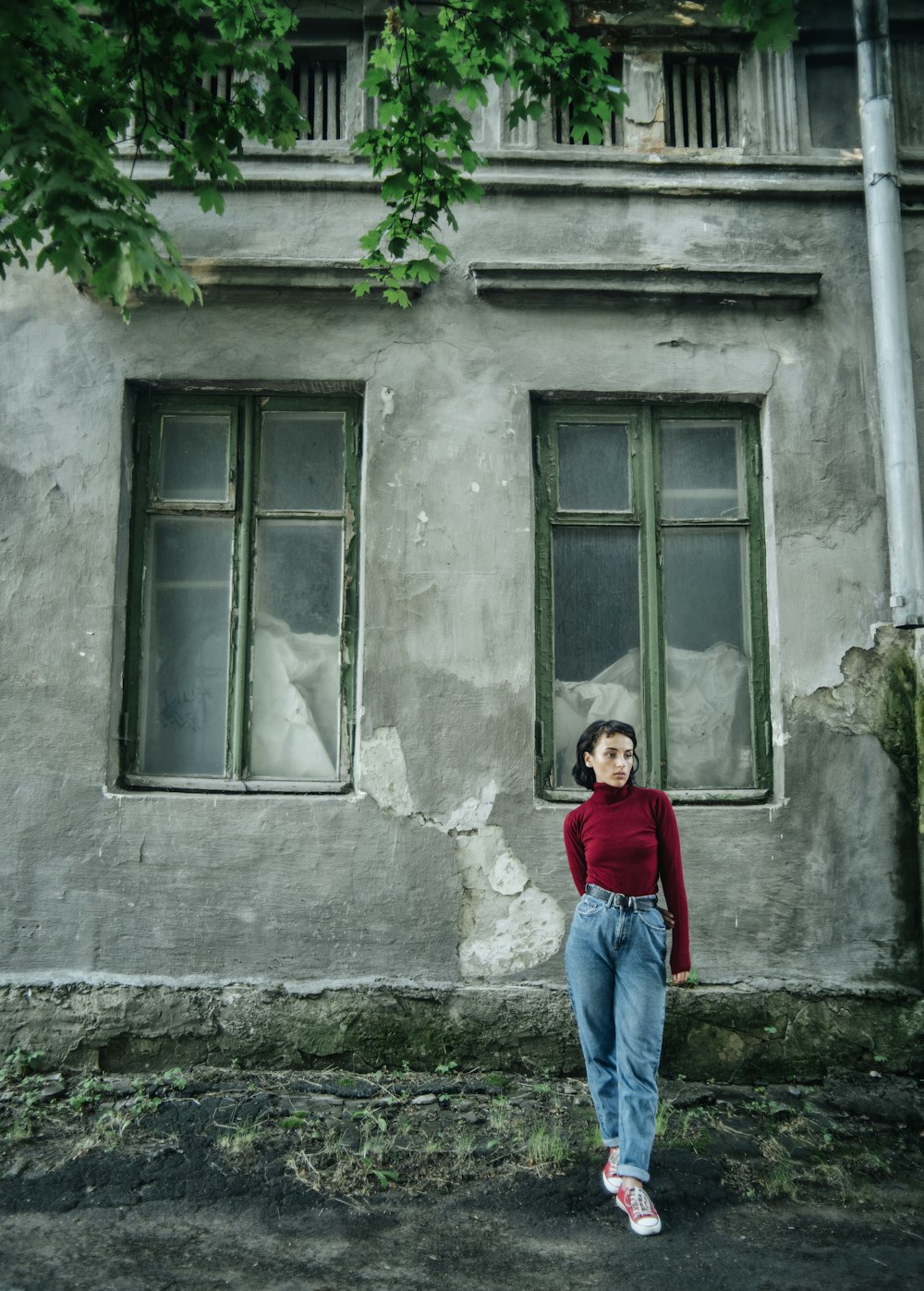 girl in red long sleeve shirt and blue denim jeans standing in front of window