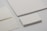 Various forms of blank stationery items are arranged, including a stack of business cards, an envelope, and sheets of paper, all placed on a neutral-colored surface.