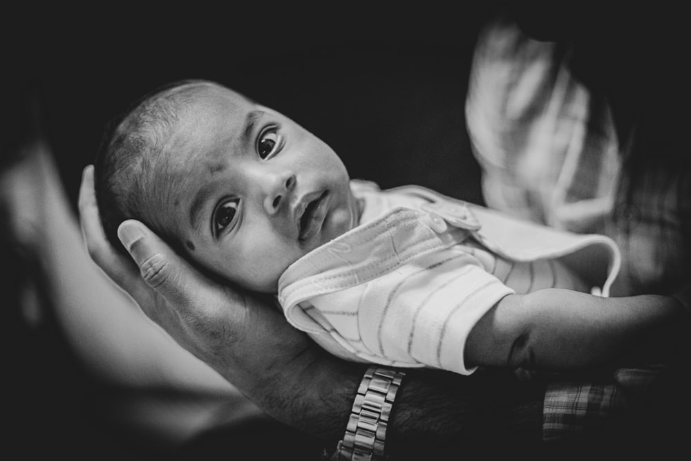 grayscale photo of baby in white and black stripe shirt