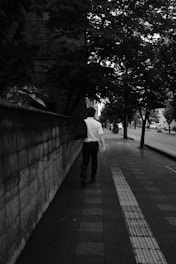 man in white dress shirt and black pants walking on sidewalk during daytime