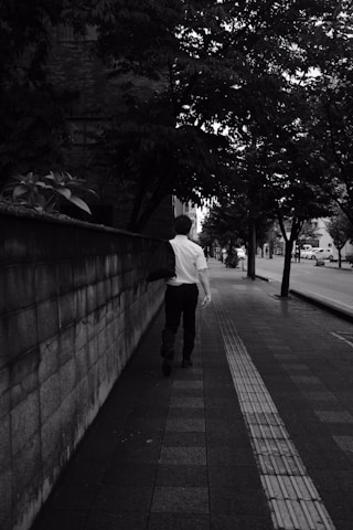 man in white dress shirt and black pants walking on sidewalk during daytime