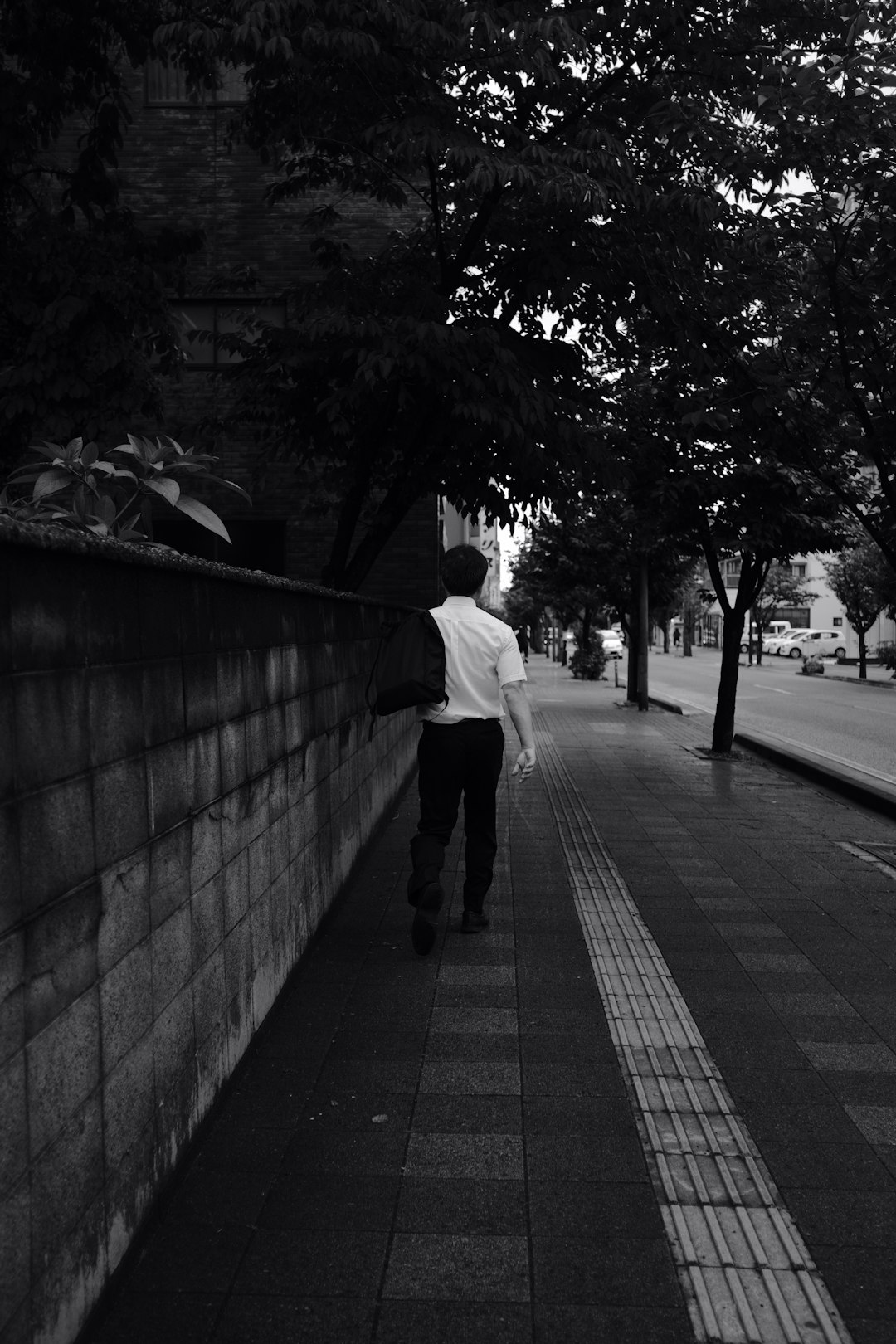 man in white dress shirt and black pants walking on sidewalk during daytime