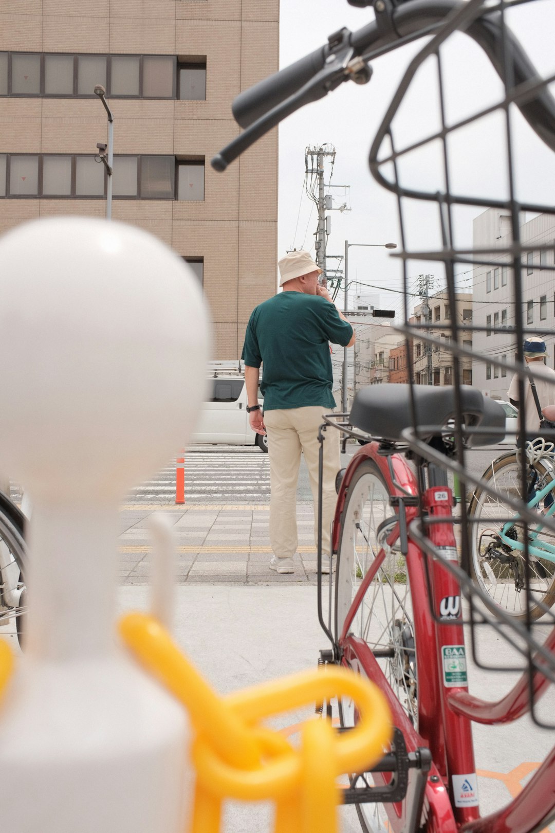 man in green shirt and black pants standing beside red city bicycle during daytime