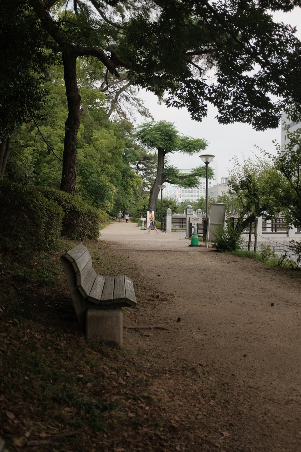 brown wooden bench near green trees during daytime