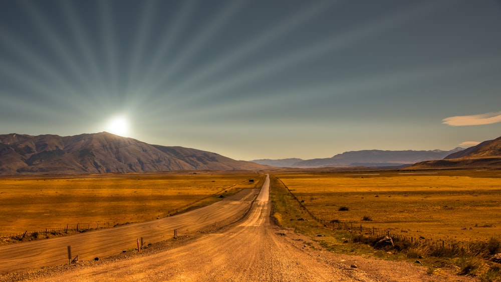 Campo marrón cerca de la montaña marrón bajo el cielo azul durante el día