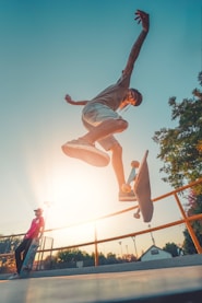 man in blue shirt and brown shorts jumping on air during daytime
