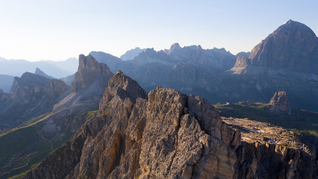 brown rocky mountain under blue sky during daytime, Flying over Passo Giau, one of the most beautiful mountain places in Italy (and probably in the world).<p></figure>You can see Rifugio Nuvolau standing proud on top of the peak, anche the Cinque Torri (five towers) behind on the right.