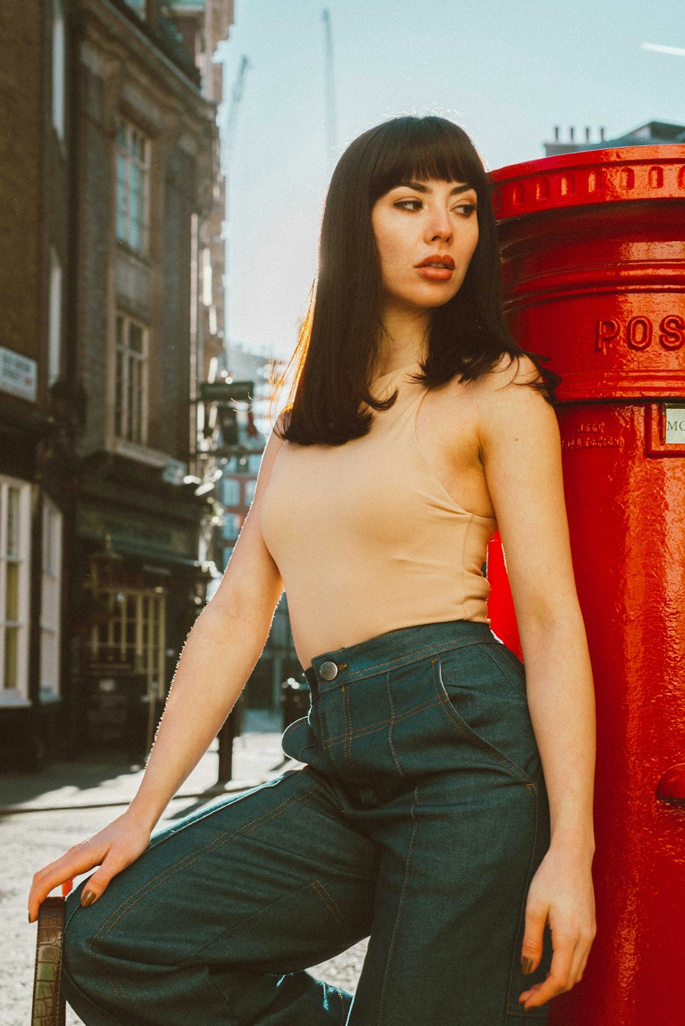 woman in blue denim jeans standing on sidewalk during daytime