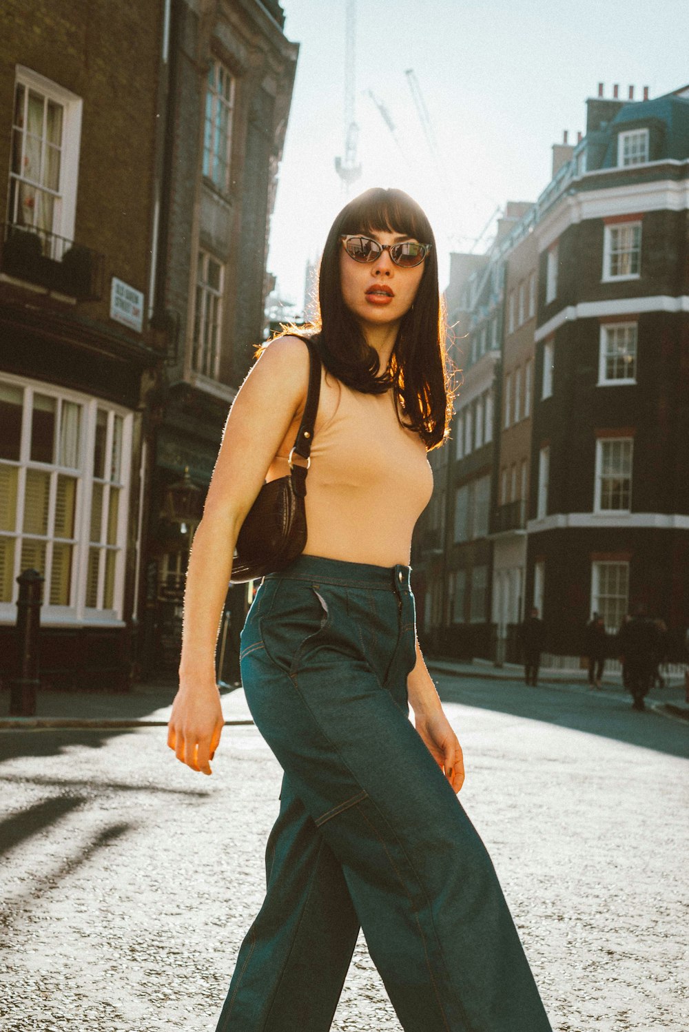 woman in black spaghetti strap top and blue denim jeans standing on gray concrete floor during