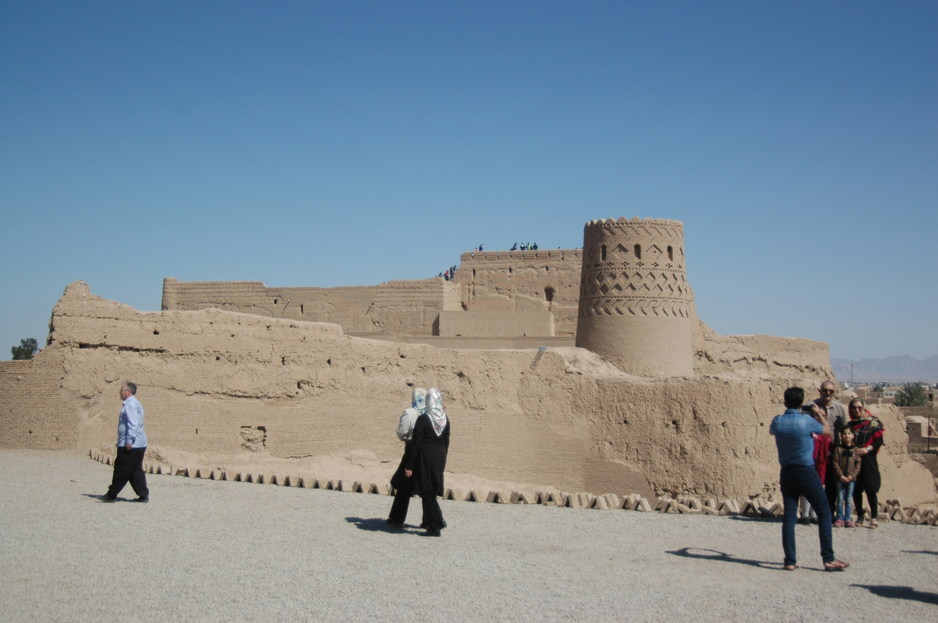 man in white dress shirt and black pants walking on gray sand during daytime