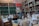 A bustling shop interior filled with packed shelves, showcasing a variety of products such as jars, cans, and bags filled with different grains and spices. Labels with handwritten prices are visible, adding a local market atmosphere. The display is well-organized, with colorful packaging and a diverse selection of goods.