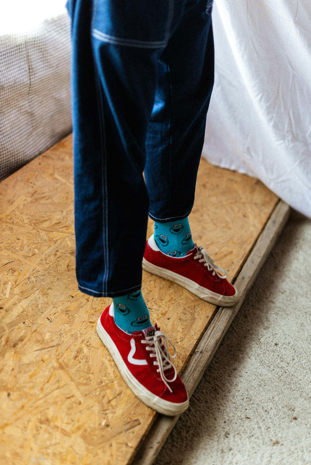 person in blue denim jeans and red converse all star high top sneakers