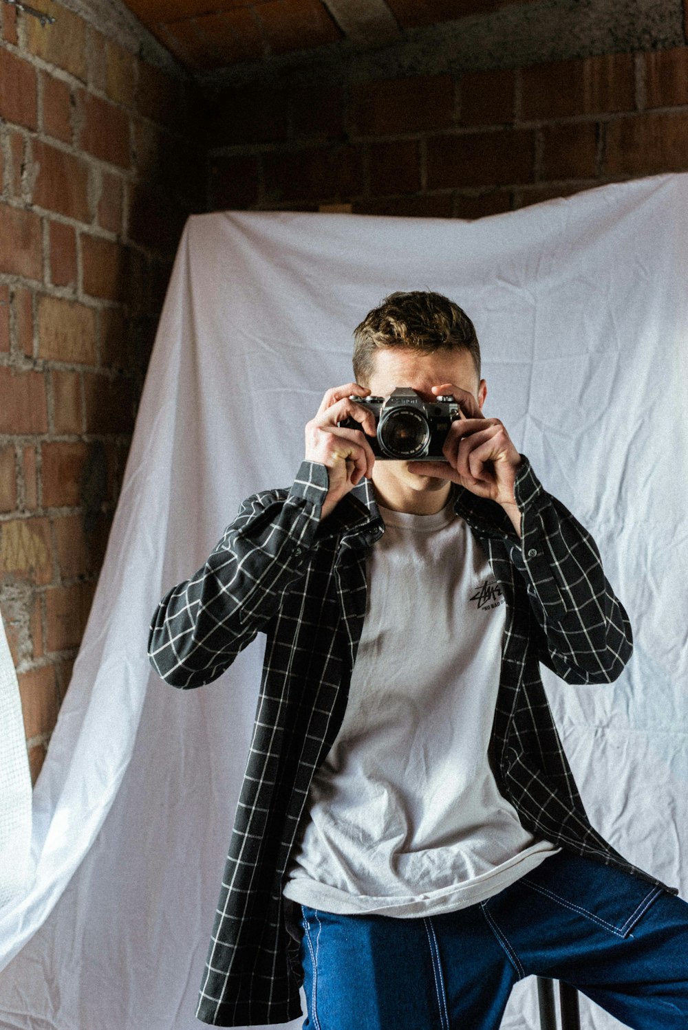 man in black and white checkered dress shirt holding black dslr camera