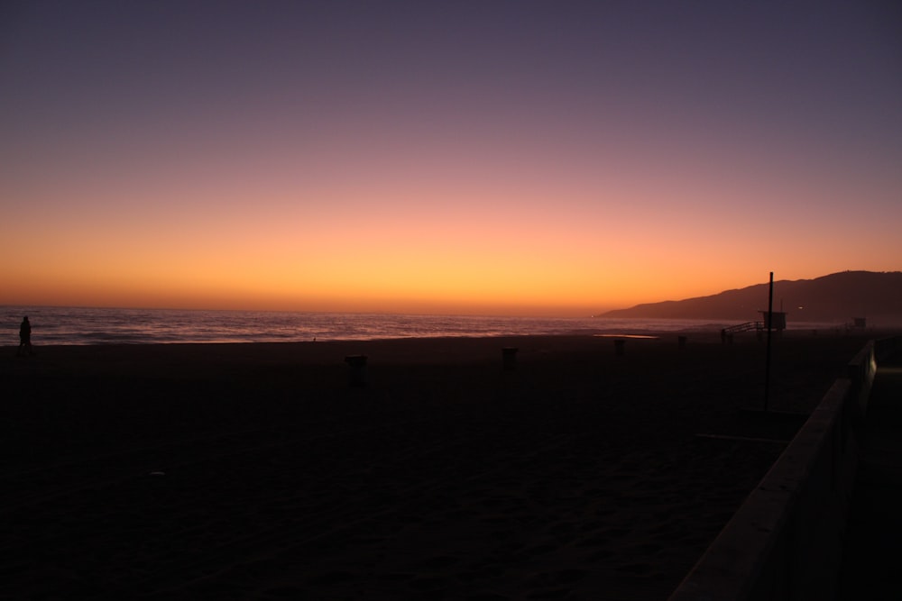 Silueta de la gente en la playa durante la puesta del sol