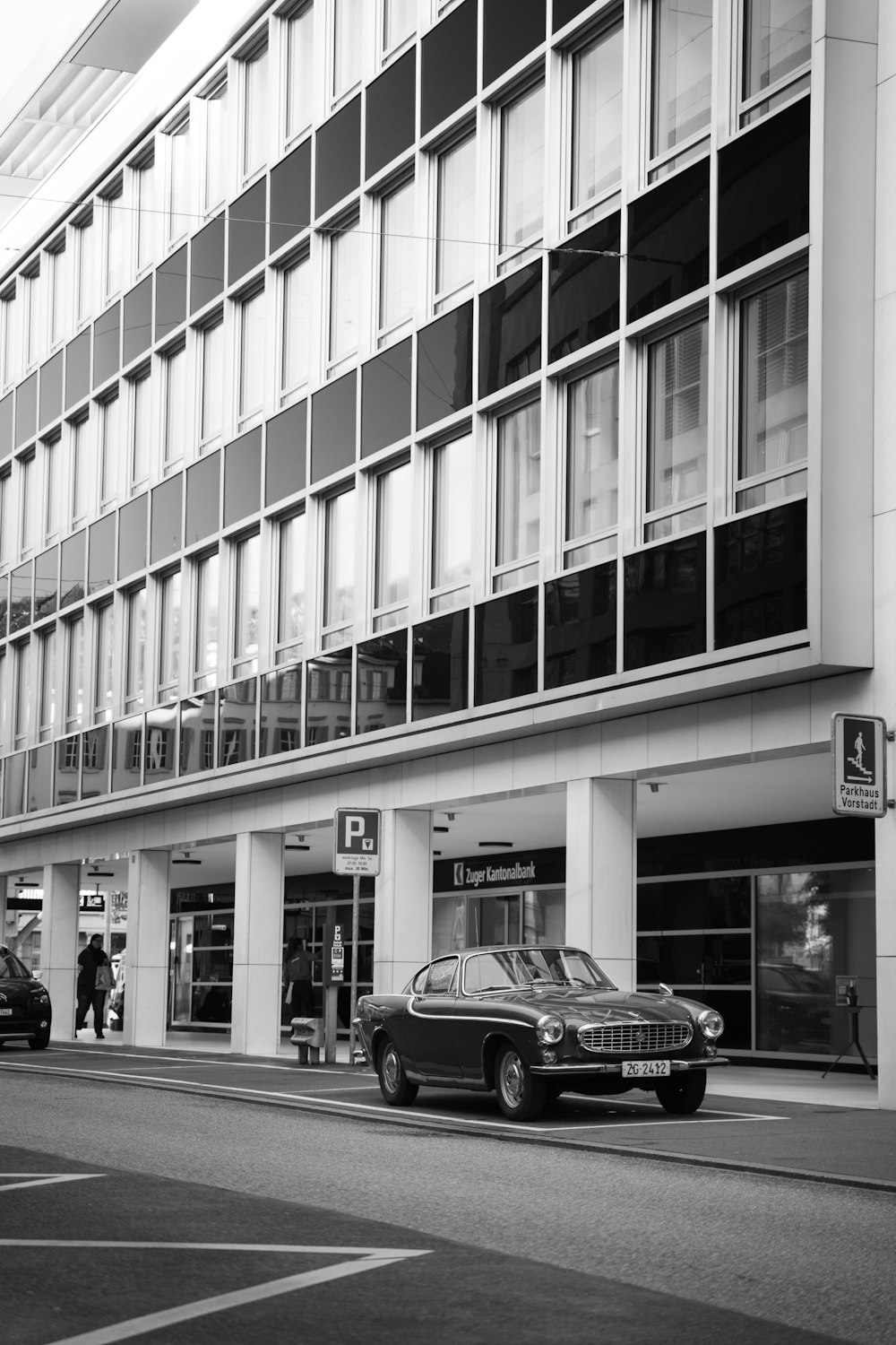 grayscale photo of car parked beside building