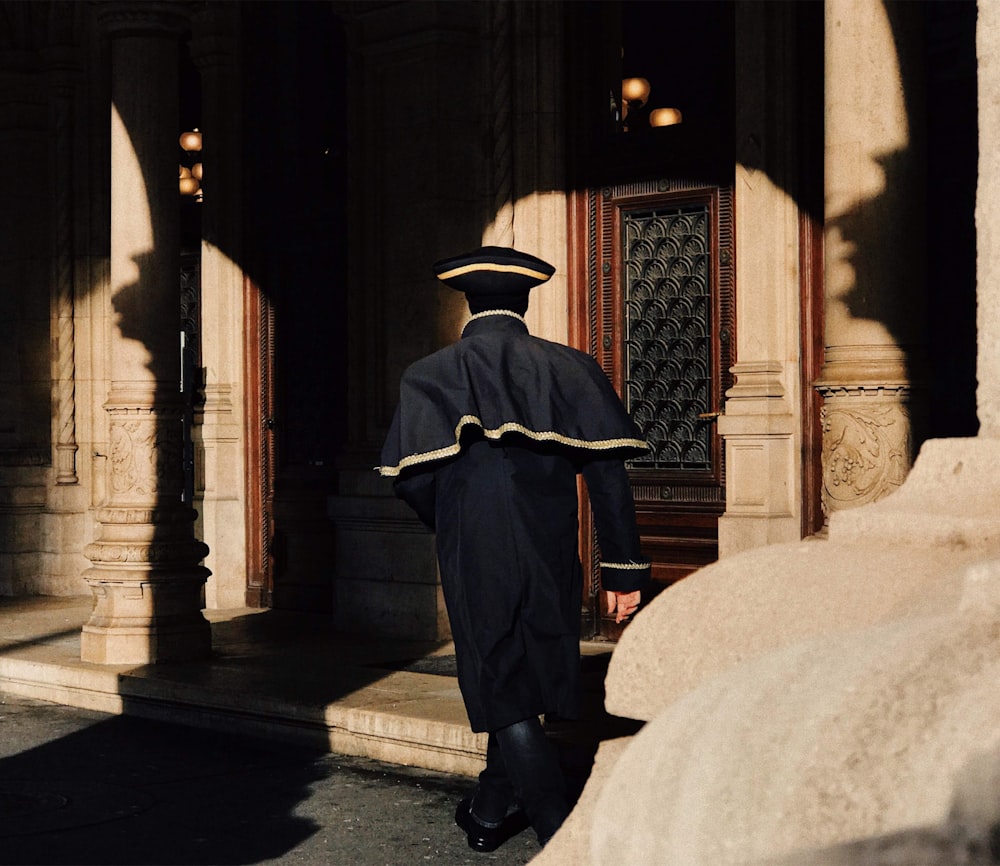 man in black coat and black hat sitting on concrete bench