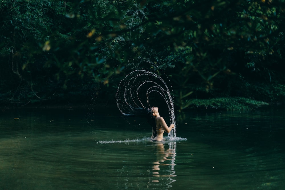 woman in water holding white string lights