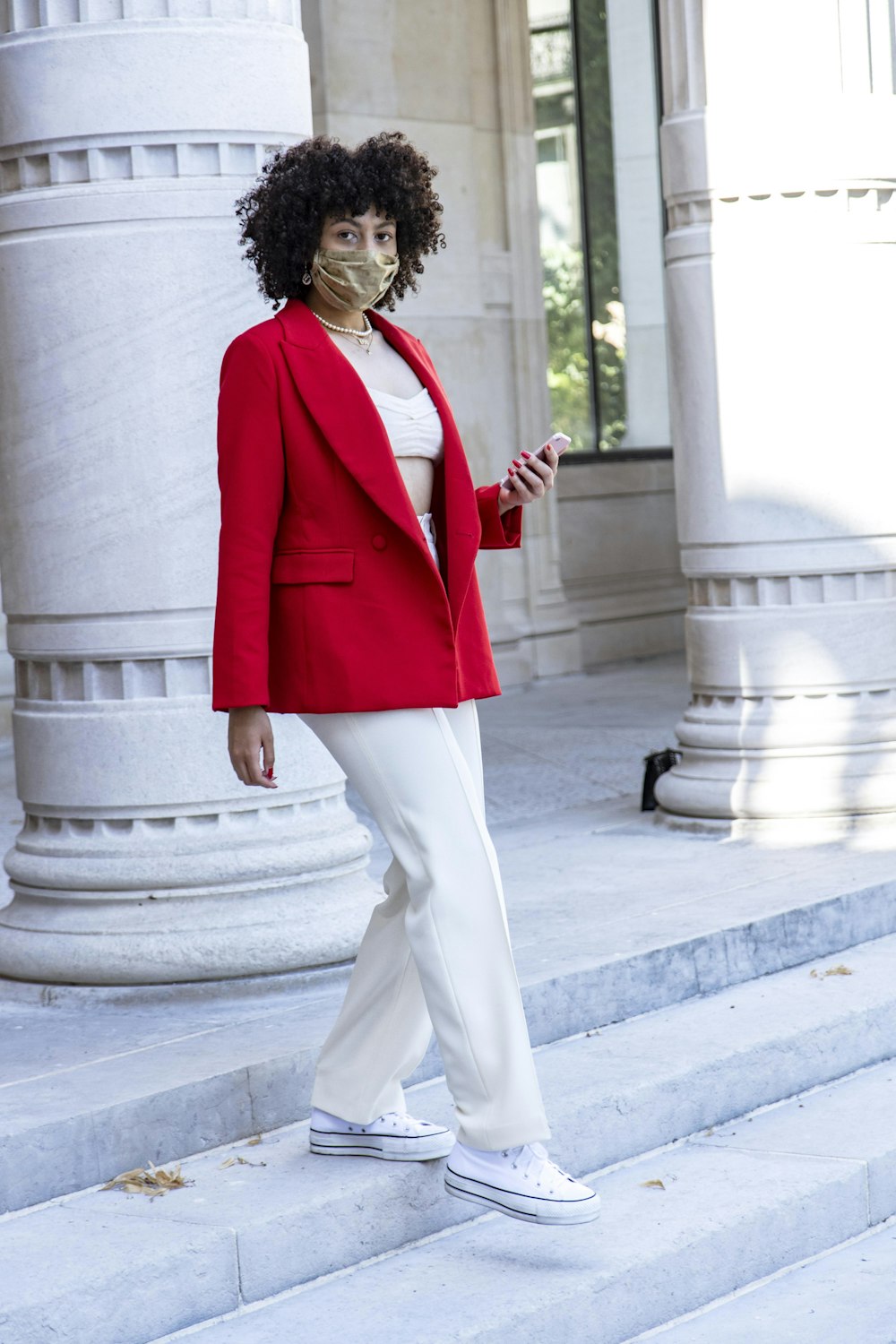 woman in red blazer and white pants standing on gray concrete stairs during daytime