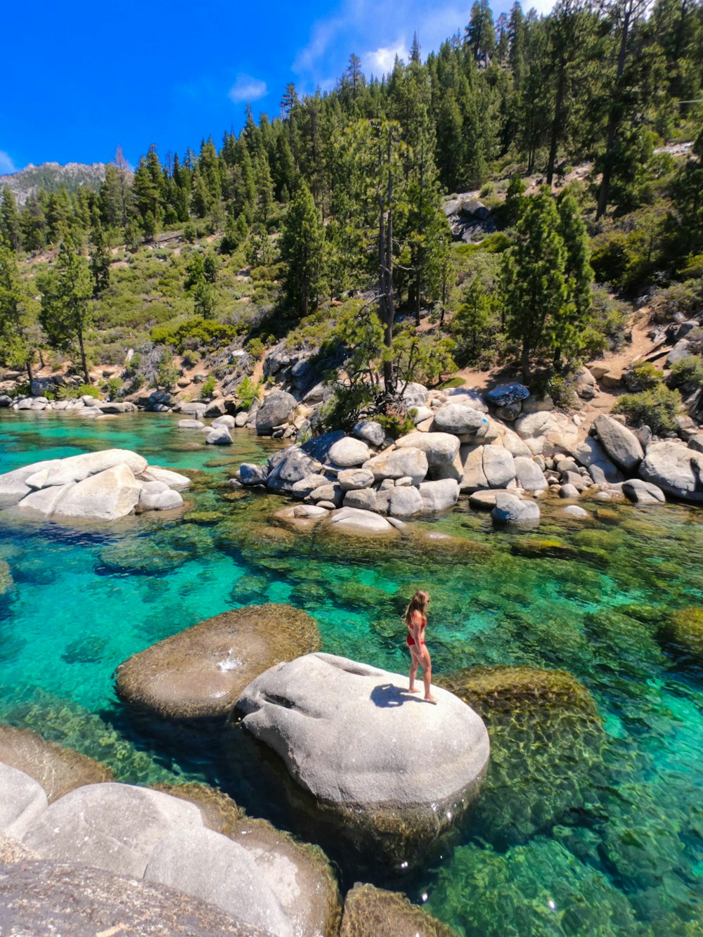 woman in black tank top standing on rock near river during daytime