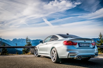 A sleek metallic grey BMW driving through a winding Bavarian mountain road at sunset.