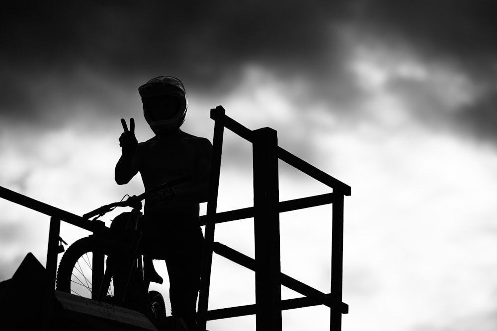 grayscale photo of man sitting on wooden ladder