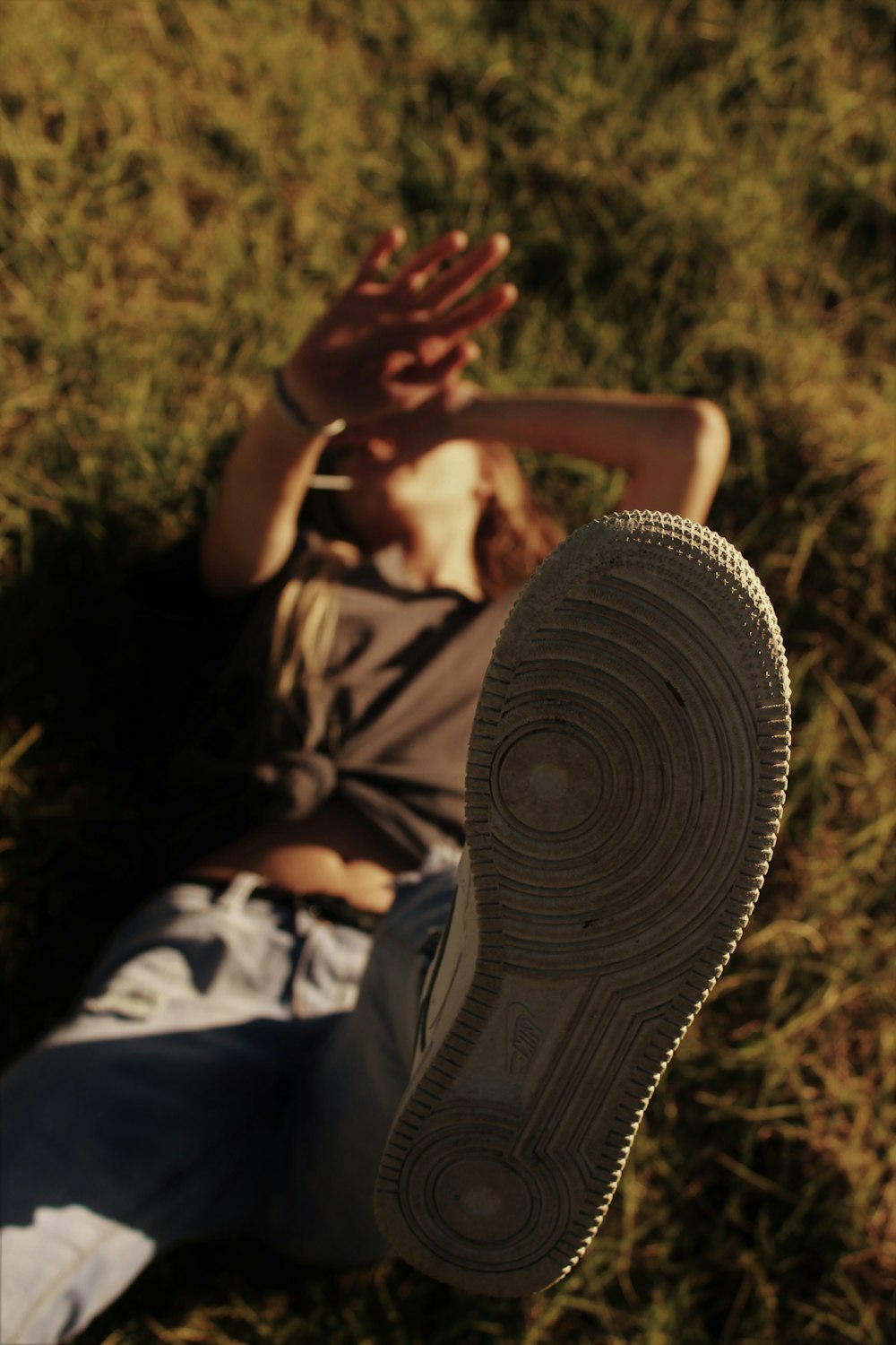 man in brown shirt and black pants sitting on grass field