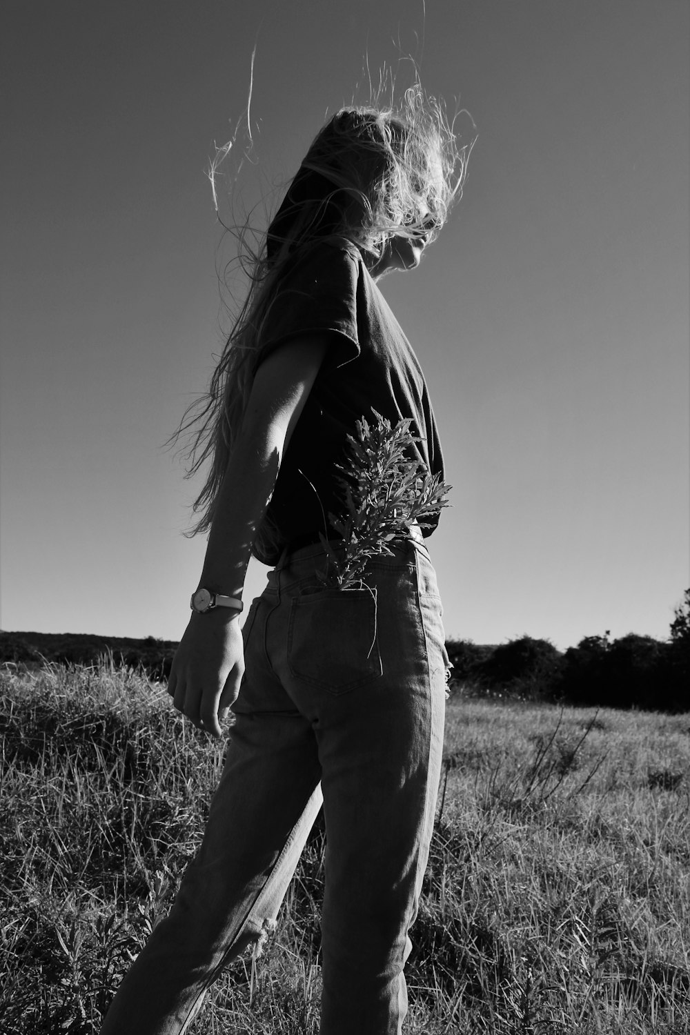 grayscale photo of woman in black tank top and pants standing on grass field
