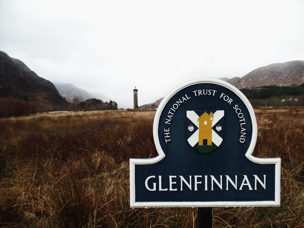 a sign in a field with mountains in the background