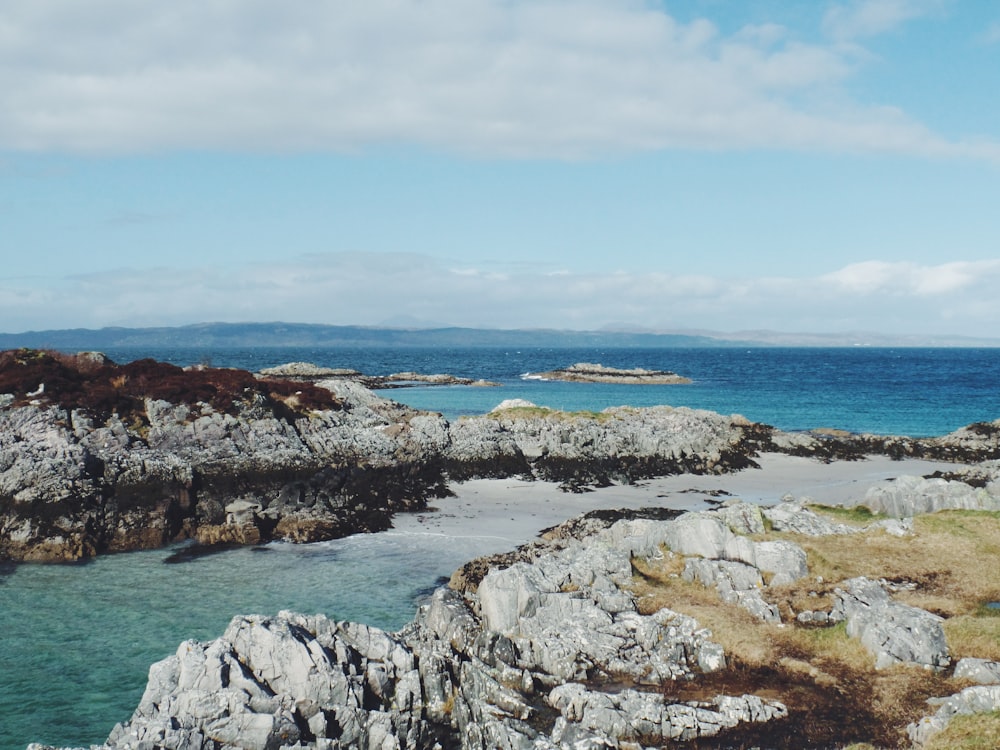 costa rocosa gris bajo el cielo azul durante el día