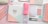 A collection of stationery items arranged neatly on a pastel-colored surface. The items include a spiral-bound planner with a geometric design, a pink pencil case with the word 'CHILL', several pastel-colored pens and pencils, notepads, glasses, and other accessories. The colors are soft and calming, predominantly pink, white, and mint green.
