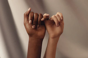 two hands with linked pinky fingers