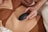 A person in brown underwear holds a dark device against their stomach. The scene is intimate and focused on personal care.