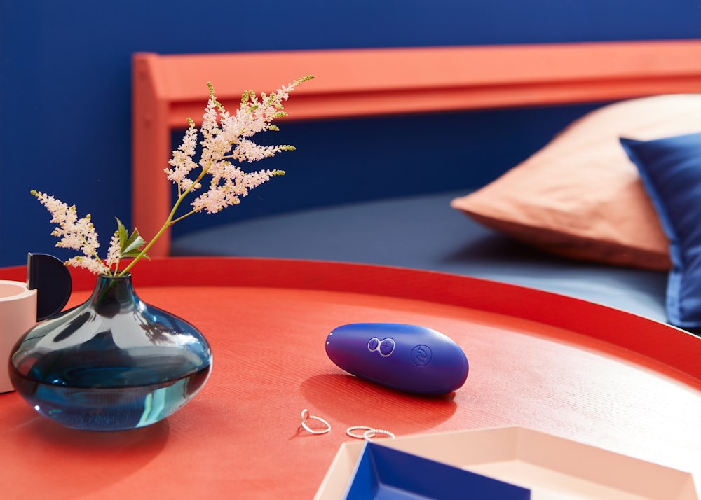 Braune und weiße Blumen in blauer Keramikvase auf braunem Holztisch