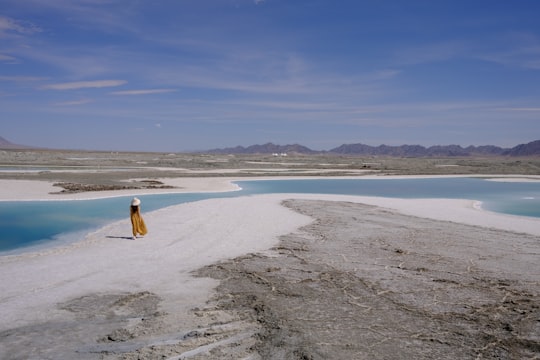 woman in white dress walking on beach during daytime in Chakayan Lake China