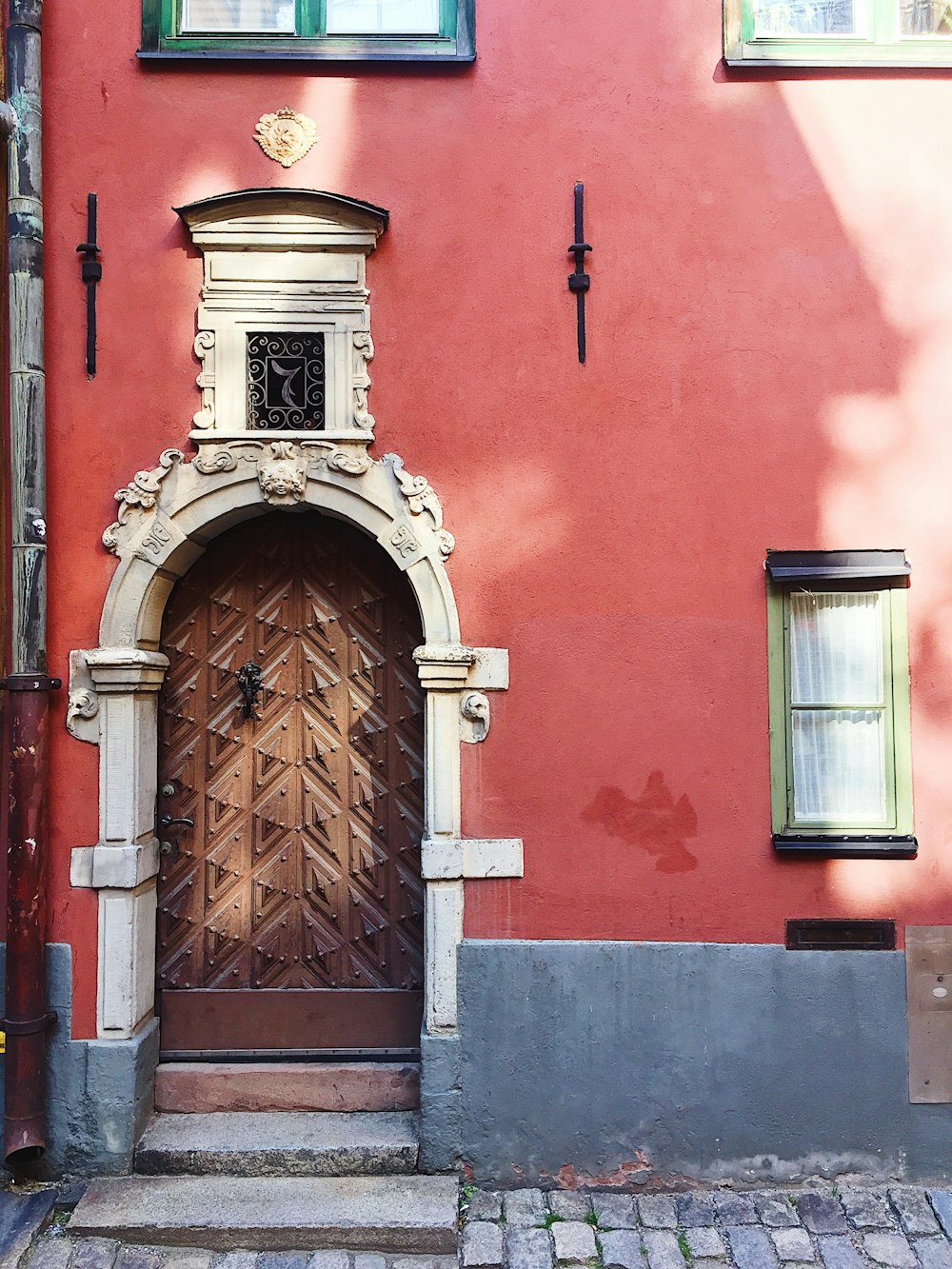 puerta de madera marrón en edificio de hormigón rojo
