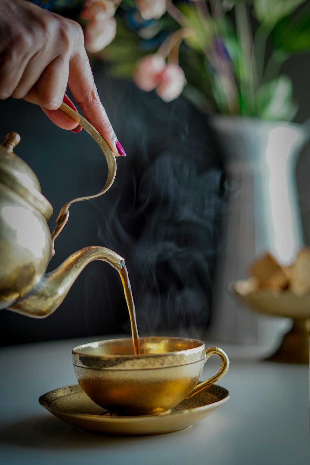 person pouring tea on white ceramic teapot