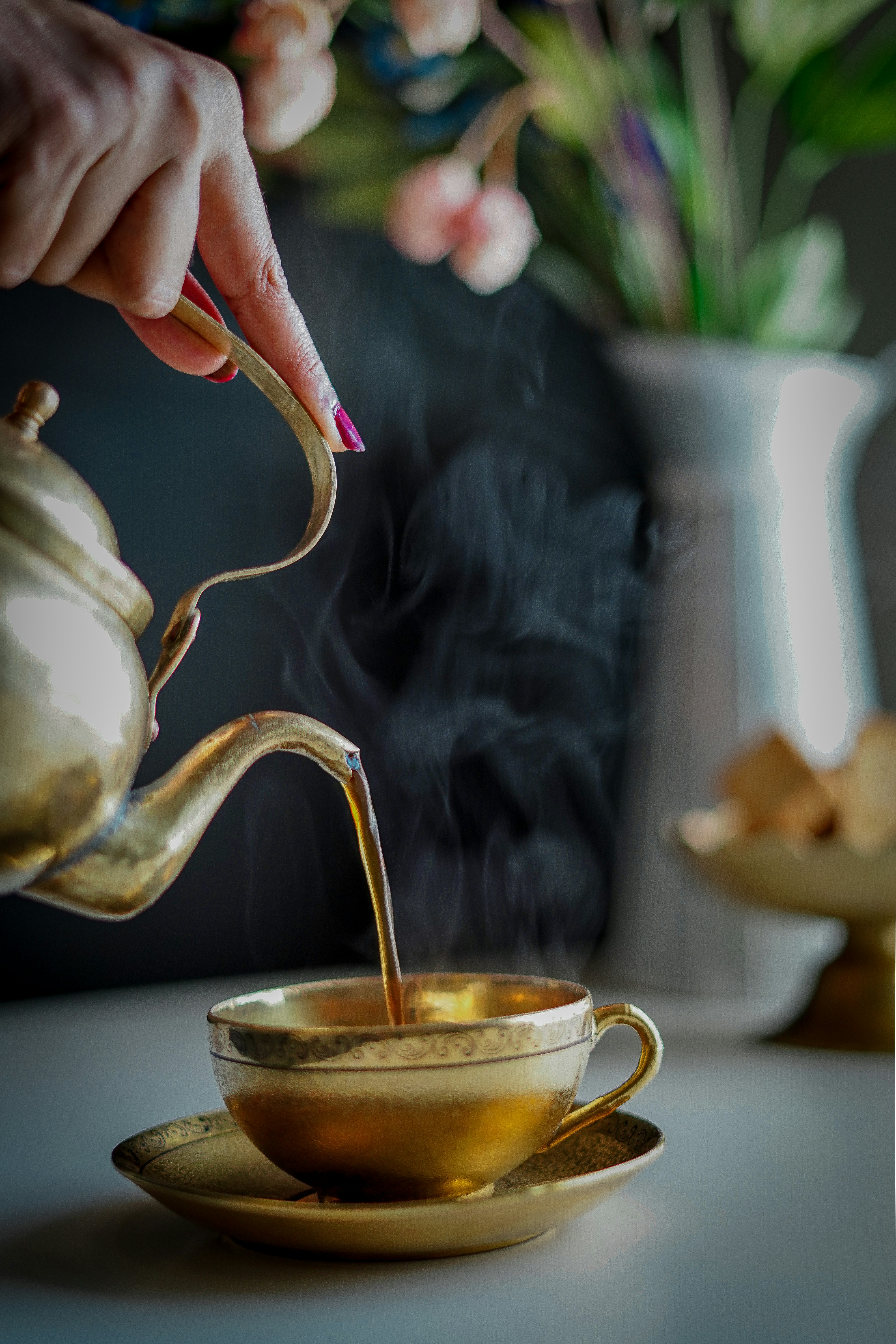 person pouring tea on white ceramic teapot