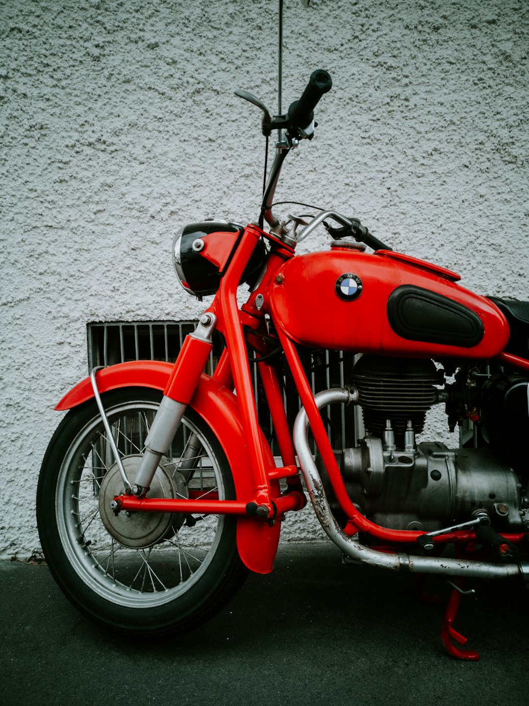 red and black motorcycle parked beside white wall