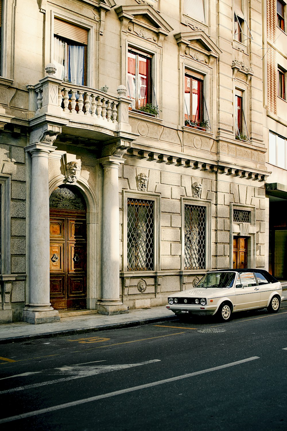 white sedan parked beside building during daytime