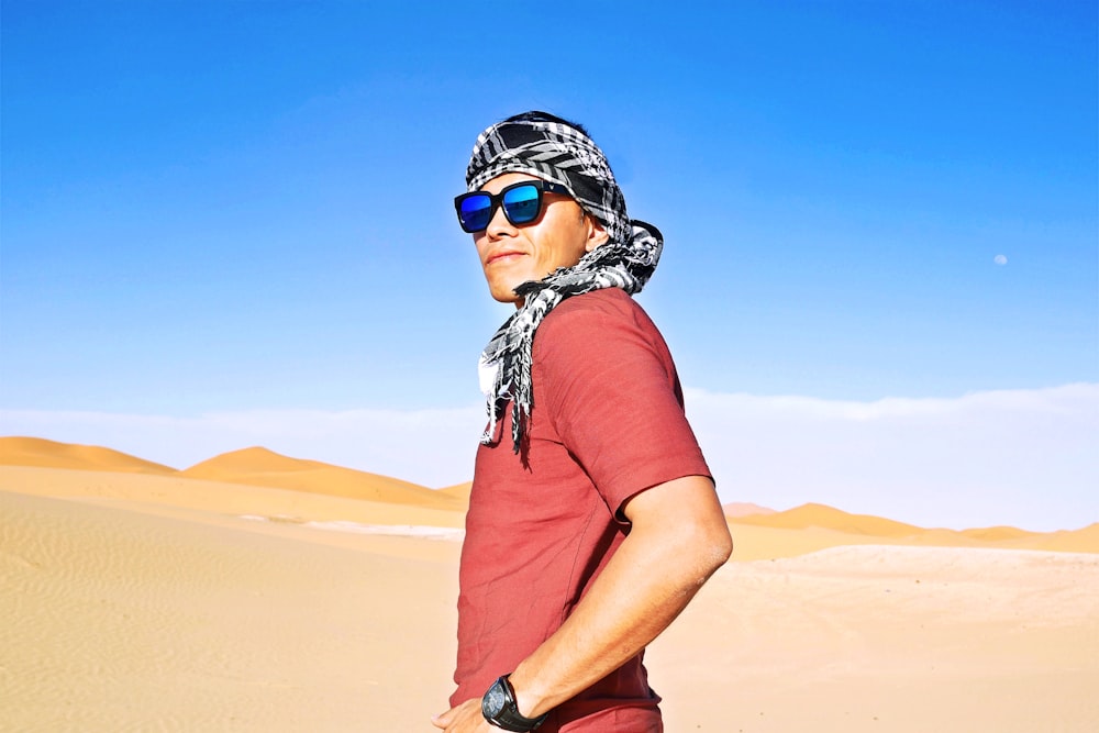 man in red t-shirt wearing black and white helmet standing on brown sand during daytime