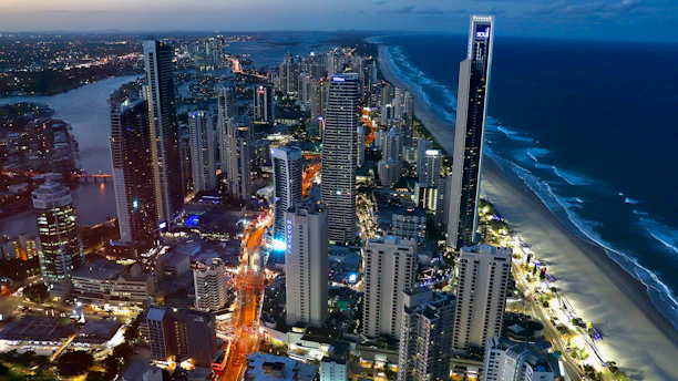 A sleek, modern satellite view of a coastal city at dusk with teal and navy overlays highlighting geospatial data points.