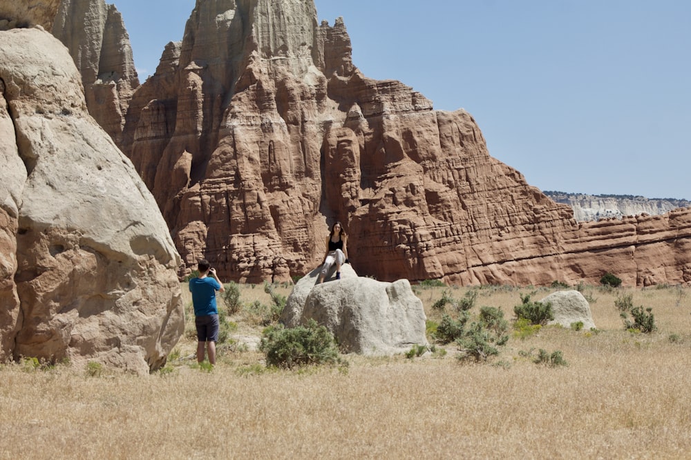 man in blue shirt and blue denim jeans standing near brown rock formation during daytime