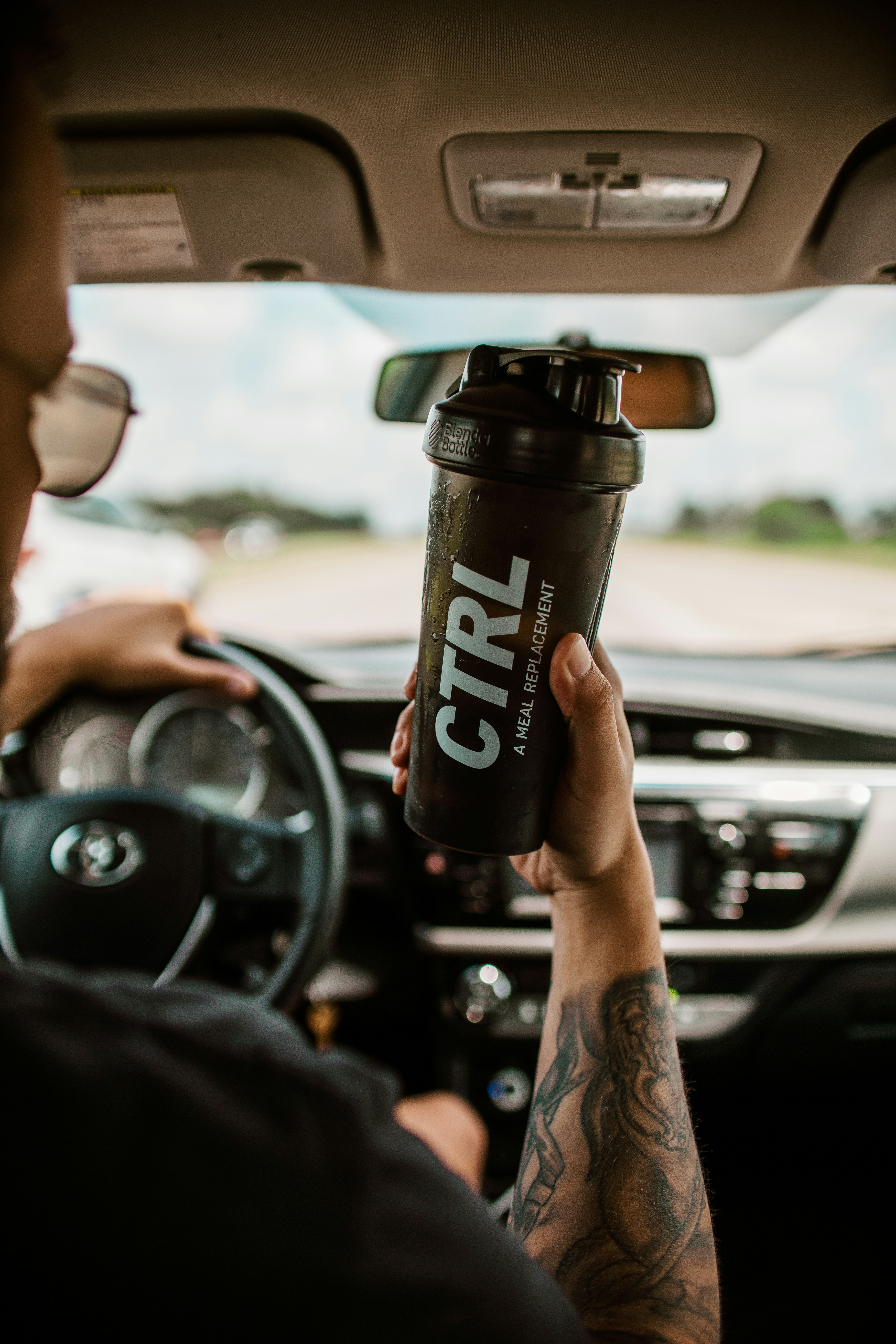 a man driving a car holding a cup of coffee
