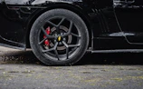 Close-up of a sleek car wheel with aggressive stance and custom brake calipers.