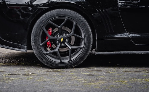 Close-up of a custom forged wheel with red brake calipers on a charcoal gray car.